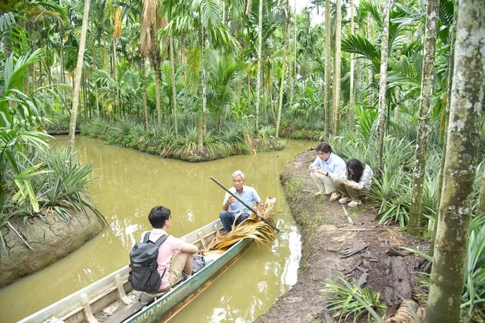 Ông Dư Văn Thái bơi xuồng qua các con kênh nhỏ, đưa học sinh Phạm Trần Duy trải nghiệm vườn cau xanh mát